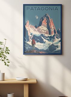 a poster hangs on the wall above a table with a potted plant in front of it