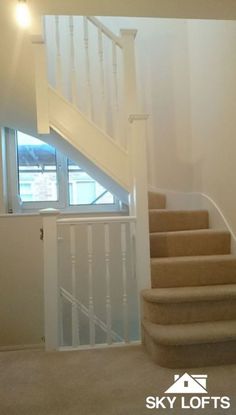 an empty room with stairs leading up to the second floor and another window in the background