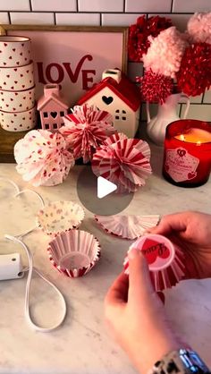 someone is decorating cupcakes with red and white decorations on the counter top