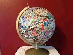 a globe covered in postage stamps on top of a white table cloth with a red wall behind it