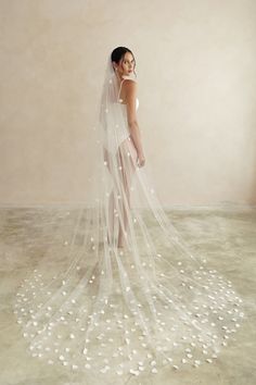 a woman wearing a wedding veil with white flowers on the floor in front of her