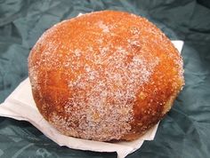 a round bread sitting on top of a piece of wax paper covered in powdered sugar