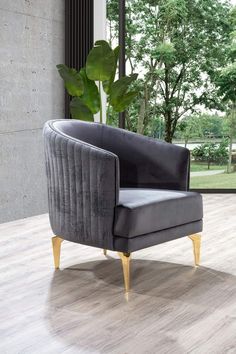 a gray chair sitting on top of a hard wood floor next to a plant in a vase