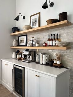 a kitchen with white cabinets and shelves filled with bottles