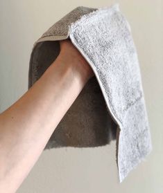 a person is holding up a towel to the wall with their hand on top of it