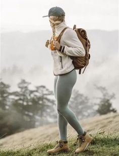 a person with a backpack and hat standing on top of a hill