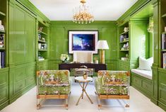 a living room filled with green furniture and a chandelier hanging from the ceiling