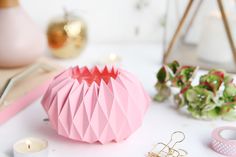 a pink vase sitting on top of a white table next to other decorations and candles