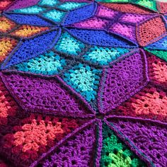 a multicolored crocheted blanket is laying on the floor