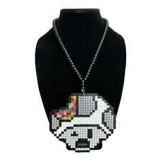 This Trippy Toad Head Handmade Perler Kandi Necklace is the perfect accessory for any festival, rave, or costume event. The necklace is made with high-quality beads and is designed by the well-known brand Byte Size Kandi. It is a unique piece of handcrafted and artisan jewelry that is perfect for those who love to stand out. The necklace features a fun and colorful toad head design that is sure to catch everyone's eye. It is a beaded necklace that is comfortable to wear and will complement any outfit. Whether you're attending a music festival or a cosplay event, this necklace is sure to add the perfect finishing touch to your look. Handmade Novelty Jewelry For Festival, Rave Style Beaded Jewelry For Festivals, Adjustable Ball Chain Beaded Necklaces As Gift, Adjustable Beaded Necklaces With Ball Chain For Gifts, Handmade Round Beads Rave Jewelry, Rave Beaded Jewelry For Festivals, Handmade Round Bead Rave Jewelry, Novelty Beaded Jewelry For Festivals, Adjustable Beaded Ball Chain Necklace For Gifts