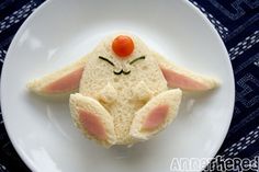 a white plate topped with a piece of bread shaped like a bunny face and carrot nose