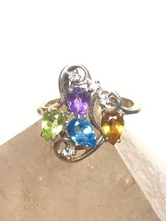 "Cocktail ring sparkly colored stones blue pink yellow pinky sterling silver women girls Size 6.75 Weight 3g Length. 3/4\" Widest 5/8\" Thinnest part of band 3/32\" Free Shipping & Free Postal Insurance Delivered in a Gift Box If you do not want the ring polished and want to leave the natural patina please let me know at the time of purchase as I do polish rings before I ship rings out. Thanks Free First Class shipping and postal insurance is included. If you want to upgrade to priority kind Formal Multi-stone Crystal Ring In Sterling Silver, Multicolor Multi-stone Cubic Zirconia Rings, Multicolor Multi-stone Crystal Ring Gift, Elegant Blue Multi-stone Crystal Ring, Silver Cubic Zirconia Crystal Ring With Multi-stones, Canoe Boat, Colored Stones, Box Making, Moonstone Ring