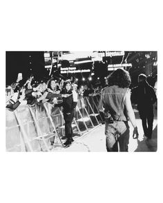 black and white photograph of people walking in front of an audience at a music festival