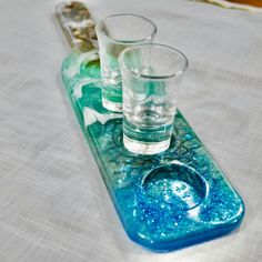 three shot glasses sitting on top of a tray with blue and green liquid in it