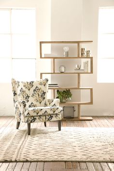 a chair sitting on top of a wooden floor next to a book shelf