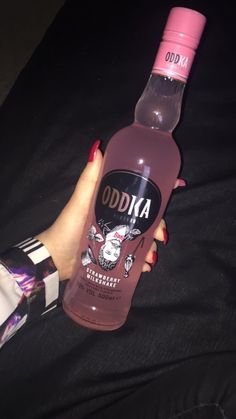 a bottle of odda vodka being held by a woman's hand on a black background