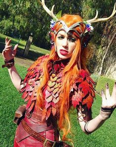 a woman dressed in costume with horns and leaves on her head, holding two hands up