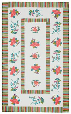 a white rug with colorful flowers and stripes on it, in the shape of a rectangle