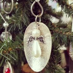 a glass ornament hanging from a christmas tree decorated with angel wings and pearls