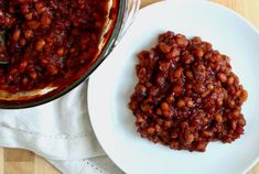 a white plate topped with beans next to a bowl of chili