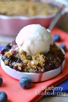 blueberry cobbler with ice cream in a bowl on a red place mat next to another dish