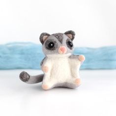 a small stuffed animal sitting on top of a white table next to some blue blankets