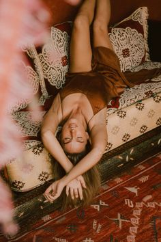 a woman laying on top of a bed next to a red and white rug in a room