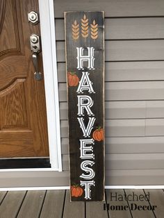 a wooden sign that says happy harvest with pumpkins and leaves on it in front of a door