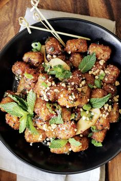 a black bowl filled with fried food and garnished with green leaves on top