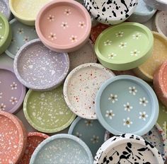 many different colored bowls are stacked together on top of each other, with speckles all over them