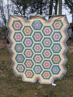 a quilt is hanging on a clothes line in the grass with trees in the background