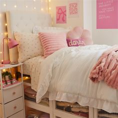 a white bed with pink pillows and blankets