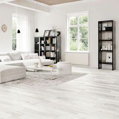 a living room with white furniture and wood floors