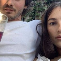 a man and woman sitting next to each other with drinks in front of their faces