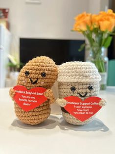 two small crocheted stuffed animals sitting next to each other on top of a table