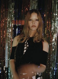 a woman with long hair standing in front of some tinsel foil curtained backdrop