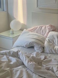 an unmade bed with white sheets and pillows