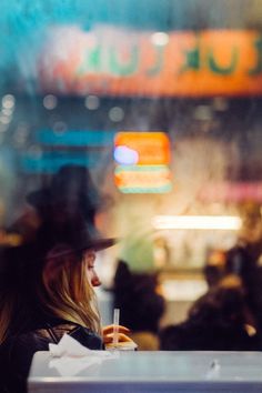 a woman sitting at a table with a drink in her hand