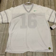 a white nike football jersey with the number 16 on it and a tag attached to it