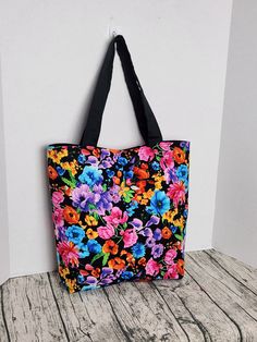 a black and pink flowered bag sitting on top of a wooden table next to a white wall