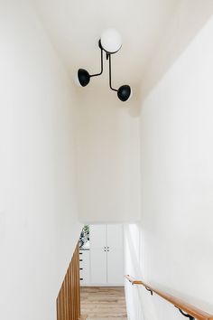 an empty hallway with white walls and wooden stairs leading up to the second floor area