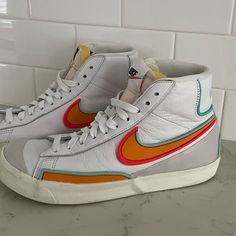 Nike Blazer Mid '77 Vintage Size: Us Women’s 7.5 Color: Primarily White Leather Upper With Bright Multicolored Swooshes (Orange, Red, And Light Blue Outlines). Design: Classic High-Top Silhouette With A Retro Vintage Style, Padded Exposed Foam Tongue, And White Laces. Outsole: Rubber Sole With A Herringbone Pattern For Traction. Condition: Good/Used (Only Worn Once) Shoes Nike Blazer, Red And Light Blue, Blazer Mid 77 Vintage, Nike Blazer Mid 77, Nike Blazer Mid, Blazer Mid, Vintage Color, Nike Blazer, Retro Vintage Style