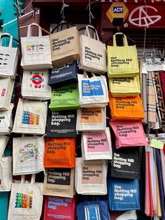 many bags are hanging up on the wall in front of a storefront with different colors and designs