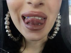 a woman with long black hair and large silver earrings on her neck is making a funny face