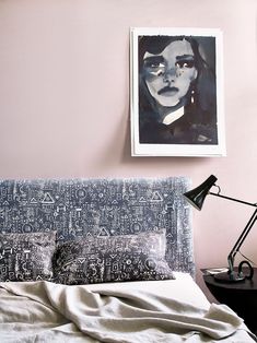 a bedroom with pink walls and an art piece on the wall above the headboard