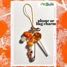 an orange and white bag charm hanging from a hook on top of a piece of paper