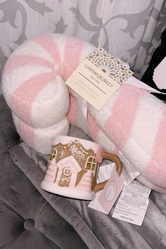 a pink and white stuffed animal with a house on it's pillow next to a cup