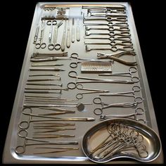 the tray is full of scissors and other medical instruments, including one large pair of scissors