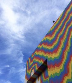 a multicolored building against a blue sky with clouds in the backround