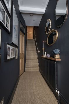 a hallway with blue walls and pictures hanging on the wall next to an entry way